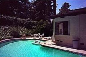 A pool with chairs and tables in the back yard.