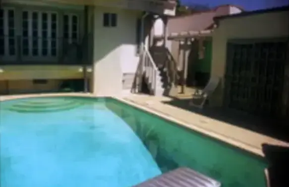 A pool with stairs and a slide in the background.