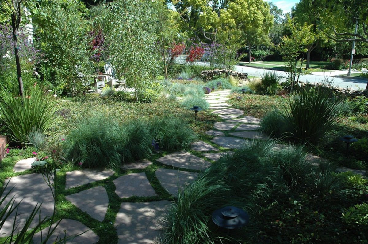 A garden with grass and trees in the background.
